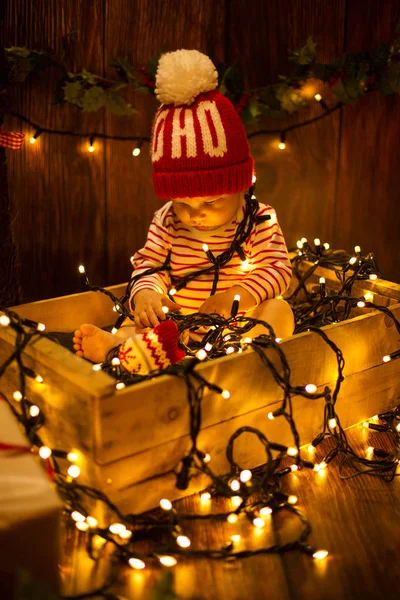 Ребенок в шляпе сидит в рождественских огнях — стоковое фото