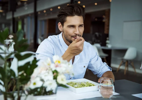 Красивый мужчина ест макароны — стоковое фото