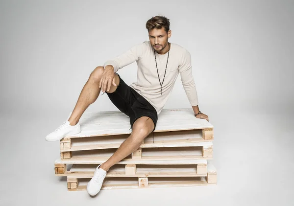 Sexy man zittend op pallets en poseren — Stockfoto