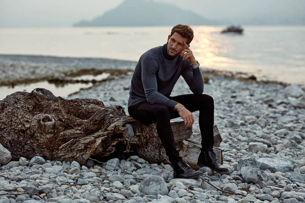 Модная мужская модель на открытом воздухе, сидящая у озера — стоковое фото