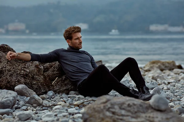 Modelo masculino de moda sentado al aire libre cerca del lago — Foto de Stock