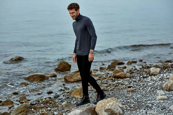 Handsome man in autumn outfit walking on the beach — Stok fotoğraf