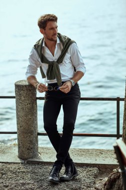 Stylish man in white classic shirt, with tied sweater on back re