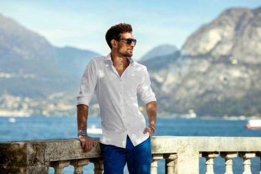 Portrait of handsome man in elegant white shirt  relaxing outdoor near the lake