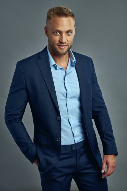 Handsome man in navy blue suit isolated on gray background