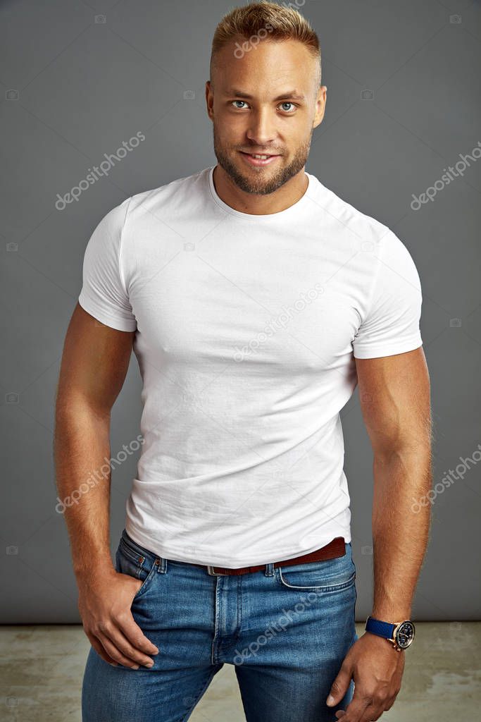 Handsome man in white t-shirt, looking at camera isolated on gray background