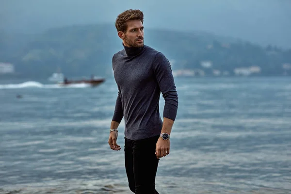 Hombre guapo en ropa de moda caminando por la playa — Foto de Stock