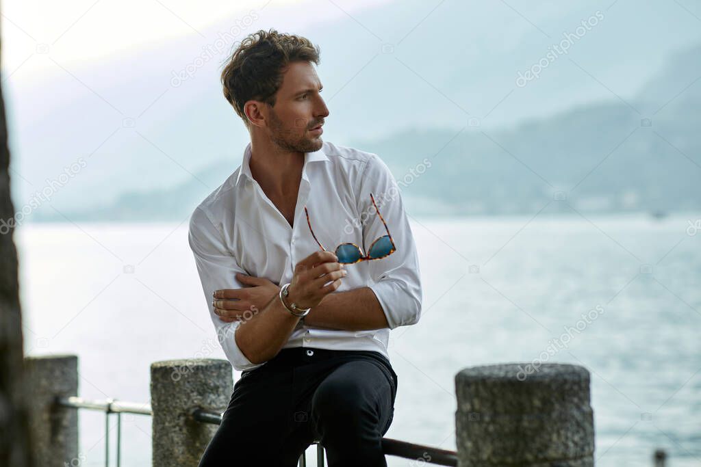 Stylish man wearing white shirt and chillin outdoor near the mou