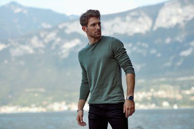 Handsome man in casual style clothes over blured mountain backgr