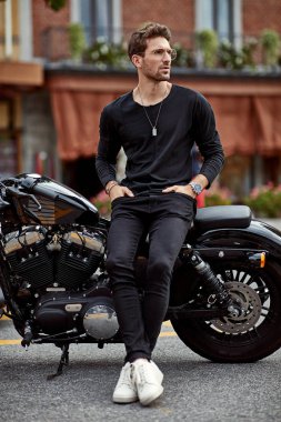 Handsome man in black sitting on american classic motorbike 