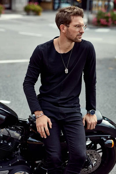 Schöner Mann in schwarz sitzt auf klassischem Motorrad — Stockfoto