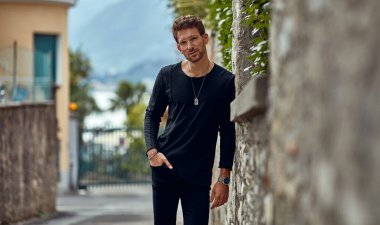 Handsome man in black outfit looking at the camera on the street