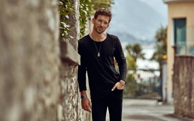 Handsome man in black outfit looking at the camera on the street