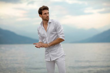 Handsome male model thinking outdoor on a background of lake and