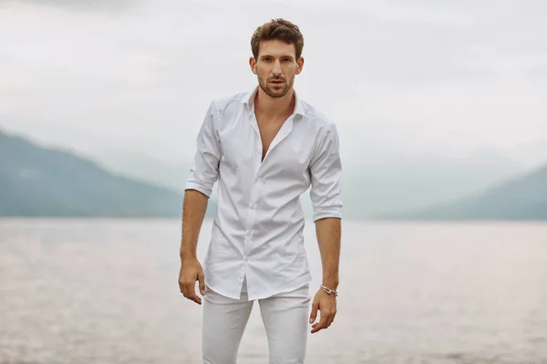 Guapo modelo masculino posando sobre un fondo de lago y montañas — Foto de Stock