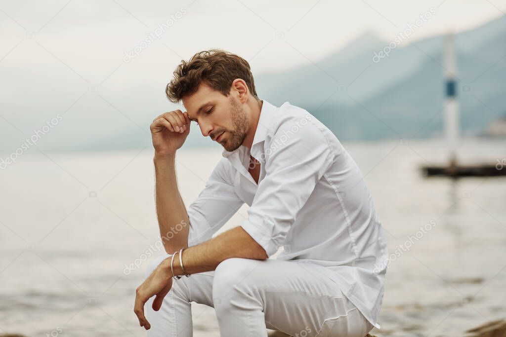 Handsome male model thinking outdoor on a background of lake and
