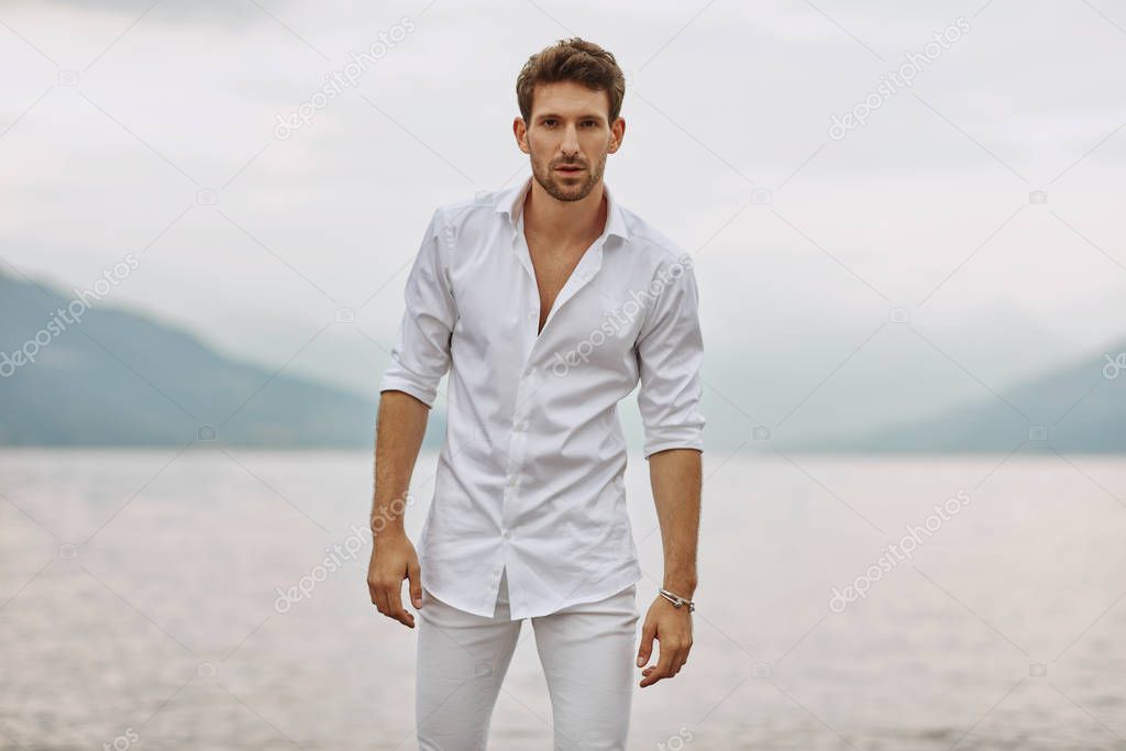 Handsome male model posing on a background of lake and mountains