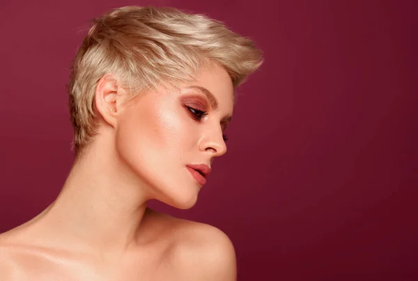 Portrait of seductive blonde woman with short hairstyle on red background