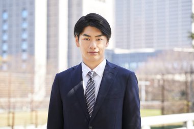 Japon bir erkek işadamı bir binanın arka planında duruyor..