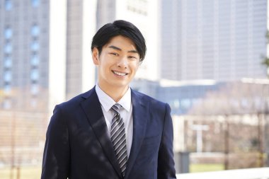 Japon bir erkek işadamı bir binanın arka planında duruyor..