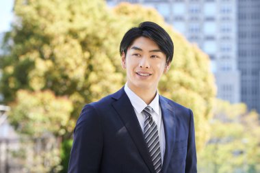 Japon erkek işadamı bir ağacın arkasında duruyor..