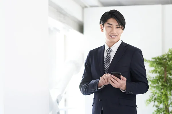 Japansk Mandlig Forretningsmand Bruger Sin Smartphone Med Smil Ansigtet - Stock-foto