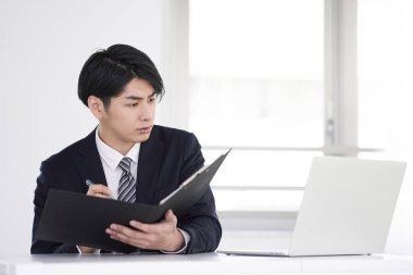 Bir Japon erkek işadamı evde takım elbise içinde malzeme hazırlıyor..