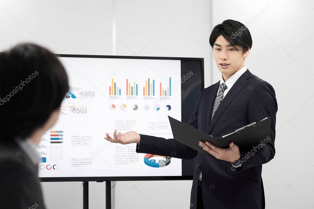 A Japanese male businessman giving a presentation.