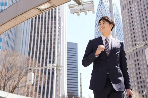 A dashing Japanese businessman walks in the office district.