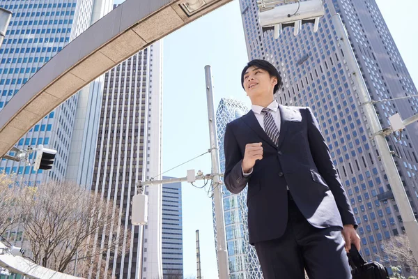 A dashing Japanese businessman walks in the office district.