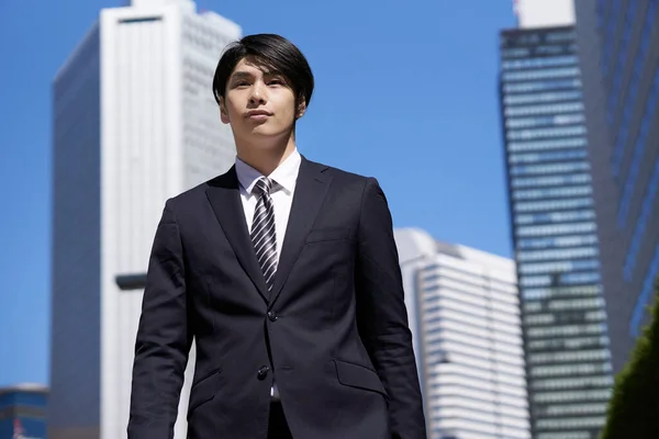 A Japanese male businessman walks through an office district.