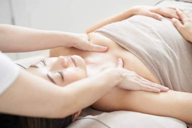 Parlak bir güzellik salonunda Japon bir kadın dekolte masaj yaptırıyor.