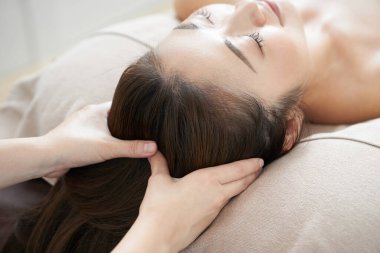 Japon bir kadın parlak bir güzellik salonunda kafa masajı yaptırıyor.