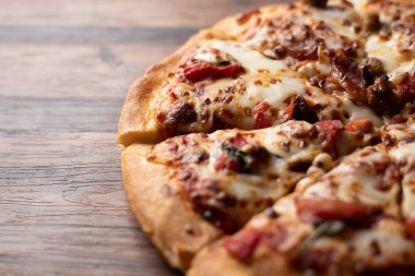 Tahta zemin üzerine kurulmuş bir pizzanın yakın çekimi.