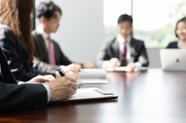 Japon bir işadamı, aydınlık bir konferans odasında toplantı yapıyor..