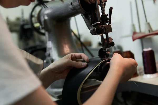 A woman\'s hand sewing leather with a sewing machine