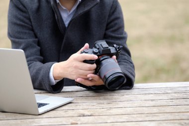 Japon bir erkek fotoğrafçı dışarıda bilgisayar ve kamera kullanıyor..