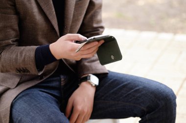 Açık havada akıllı telefon kullanan ceketli bir Japon.