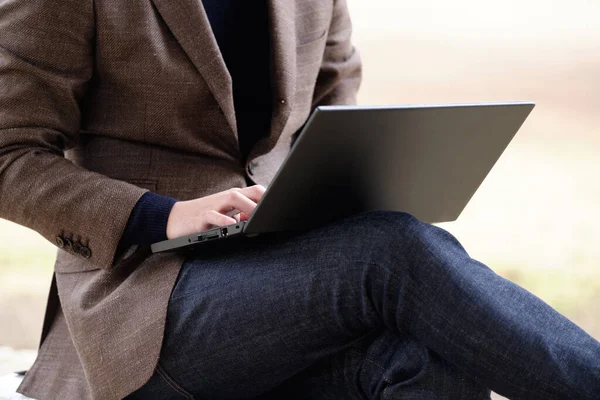 A Japanese man in a jacket operating a computer outdoors.