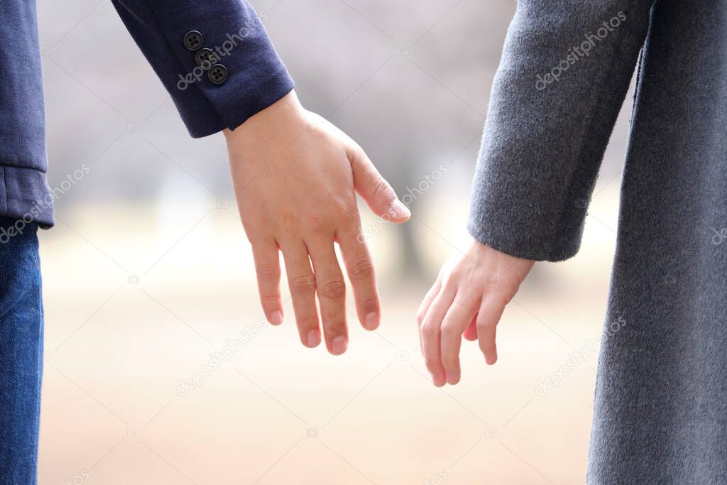 A Japanese couple tries to hold hands in a park in winter