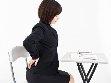 Beyaz arka planda sırt ağrısı çeken bir Japon kadın ofis çalışanı.