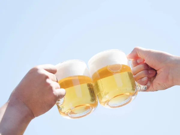 青い空の下でビールを飲みながら二人の男女が手を取り合って — ストック写真