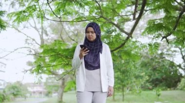 Stressed young Asian Muslim businesswoman using phone and getting bad news