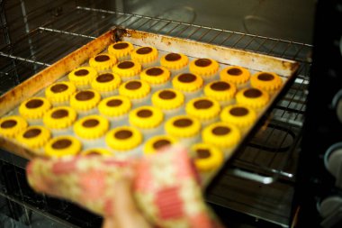 Baker fırından bir tepsi çikolatalı tart alıyor.