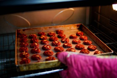 Baker fırından bir tepsi kırmızı kadife kurabiye alıyor..