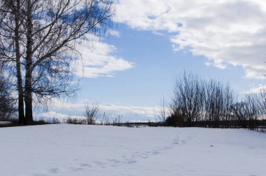 Karda ayak izleri ve baharda mavi gökyüzü.