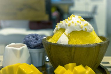 Yakın plan bingsu ya da hindistan cevizli taze krema ve mango dilimlenmiş Kore usulü tatlı pilav ve mango soslu buzlu tatlı..