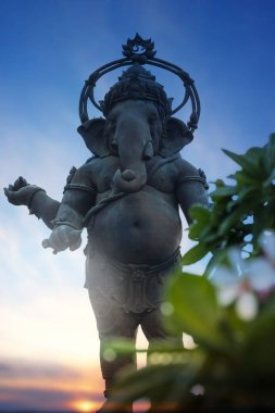 Ganesha 'nın büyük bir bronz heykeli Hindu tanrısıdır. Alacakaranlık vaktinde parkta duran en bilinen ve en tapılan tanrılardan biridir. Arka planda günbatımı vardır..