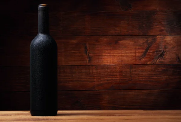 Garrafa cheia de vinho com gotas na mesa — Fotografia de Stock