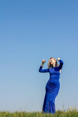 Mavi bir elbise giymiş bir kızın etrafında alanı yürüyor